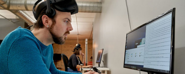 man wearing vr headset in front of computer